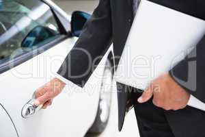 Man holding a car door handles while holding clipboard