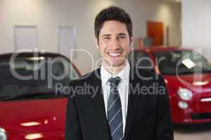 Smiling businessman standing beside a car