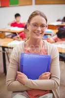 Pretty teacher smiling at camera while holding folder