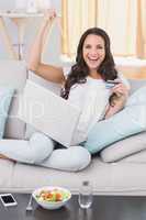 Pretty brunette shopping online on couch