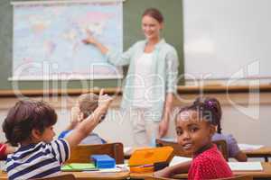 Cute pupil smiling at camera at his desk in classroom