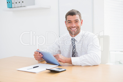 Smiling businessman using his tablet