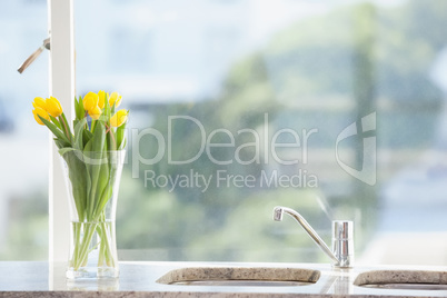 Yellow flower in a vase on the sink