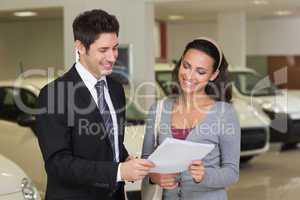 Salesperson showing clipboard to sign to customer