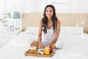 Happy brunette having breakfast in bed
