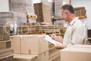 Warehouse worker checking his list on clipboard