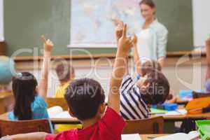 Pupils raising hand during geography lesson in classroom