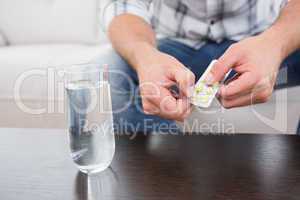Hungover man with his medicine laid out on coffee table