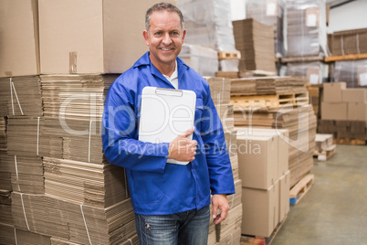 Smiling worker leaning on pile of cardboard