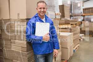 Smiling worker leaning on pile of cardboard