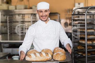 Baker holding tray of bread