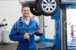 Mechanic smiling at the camera holding tool