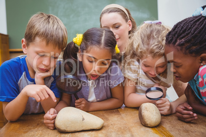 Cute pupils looking through magnifying glass