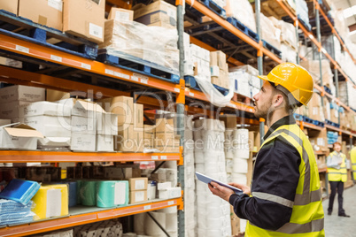 Focused warehouse manager writing on clipboard