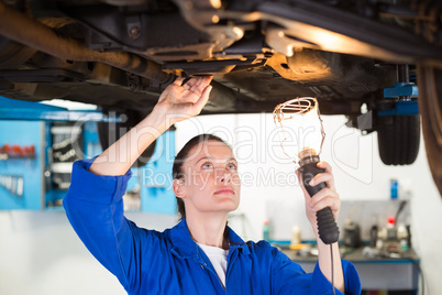 Mechanic shining torch under car