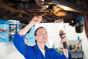 Mechanic shining torch under car