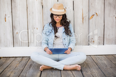 Pretty hipster sitting on ground with tablet