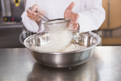 Baker sieving flour into a bowl