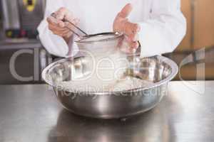 Baker sieving flour into a bowl