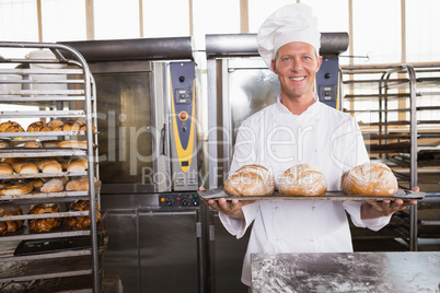 Happy baker showing tray of fresh bread