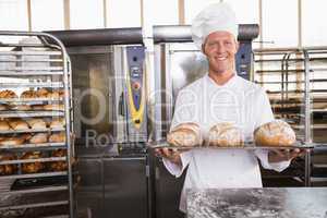 Happy baker showing tray of fresh bread