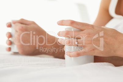 Mid section of young couple having coffee in bed