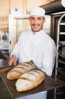 Happy baker holding tray of fresh bread