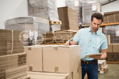 Warehouse worker checking his list on clipboard