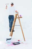 Man on ladder painting with roller