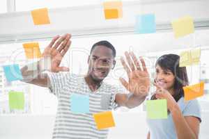 Smiling coworkers brainstorming with sticky notes