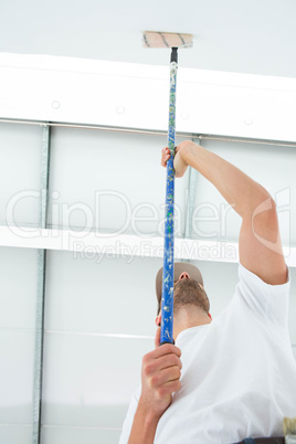 Man painting ceiling of home
