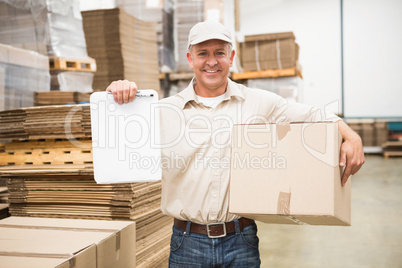 Delivery man with box and clipboard in warehouse