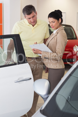 Salesperson showing clipboard to sign to customer