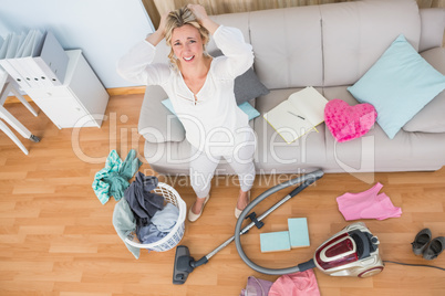 Angry woman in a chaotic living room with vacuum cleaner