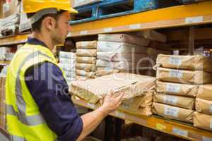 Warehouse worker taking package in the shelf