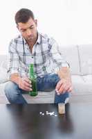 Preoccupied man  with a beer and his medicine laid