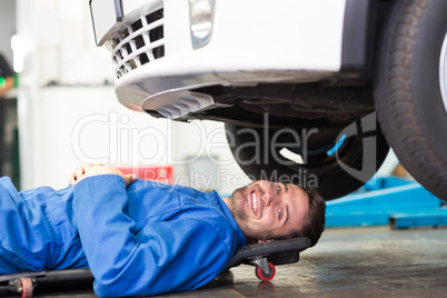 Smiling mechanic lying on trolley