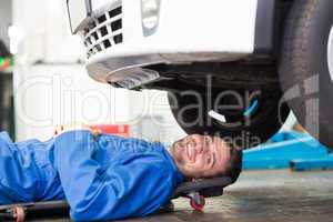 Smiling mechanic lying on trolley