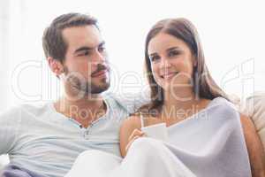 Cute couple relaxing on couch under blanket