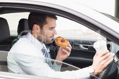 Young businessman having coffee and doughnut