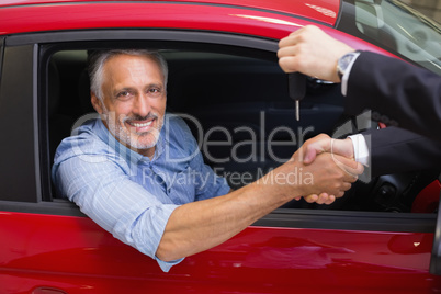 Businessman giving car key while shaking a customer hand