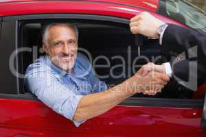 Businessman giving car key while shaking a customer hand