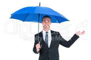 Businessman sheltering under black umbrella