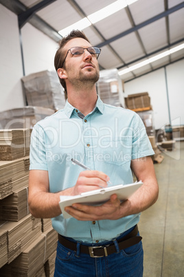 Warehouse worker checking his list on clipboard