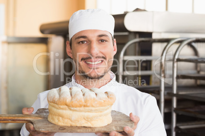 Baker showing freshly baked loaf