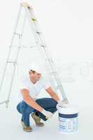 Man crouching while opening paint pot