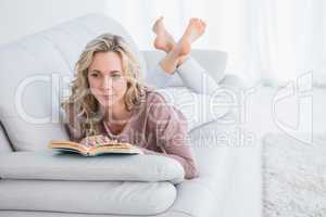 Thoughtful lying on couch reading book