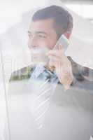 Smiling businessman looking out window on the phone