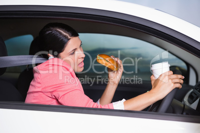 Woman drinking coffee and eating sandwich on phone