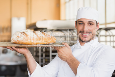 Baker holding a freshly baked loaf